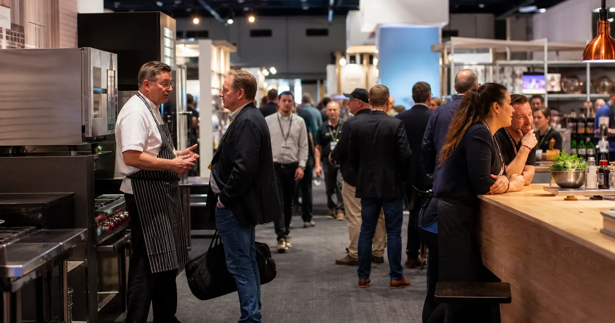 Pizza oven manufacturer demonstrating equipment to independent pizzeria owner at trade show booth